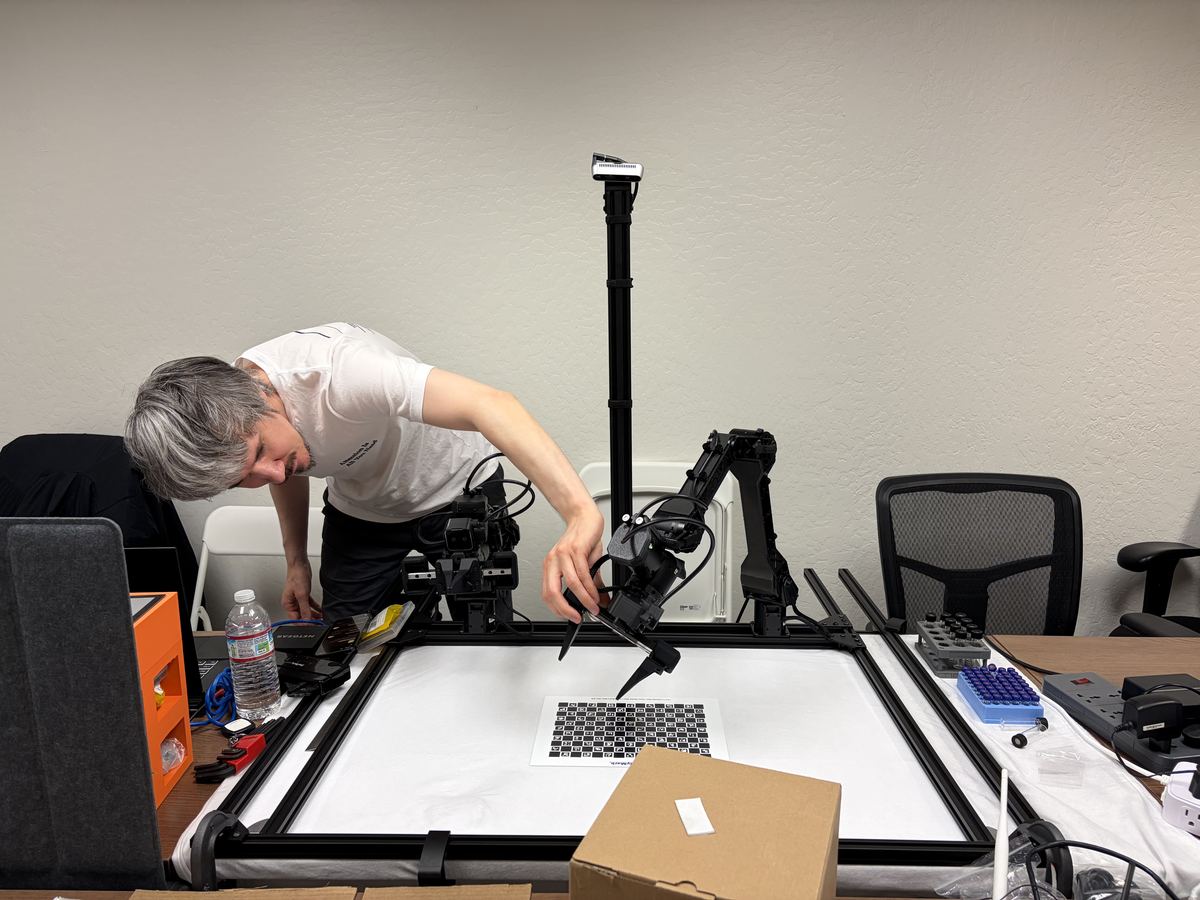Jason Meaux leaning over the test rig, adjusting the gripper above a calibration target.